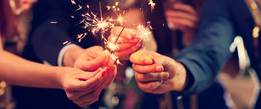 Personas festejando el 31 de diciembre con luces de bengala.