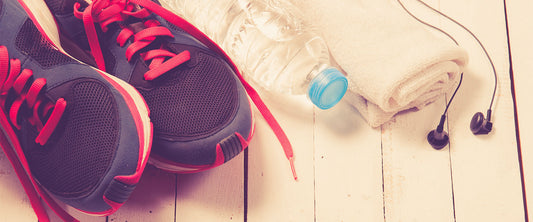 Fotografía de tenis, botellas de agua, toalla y audífonos.