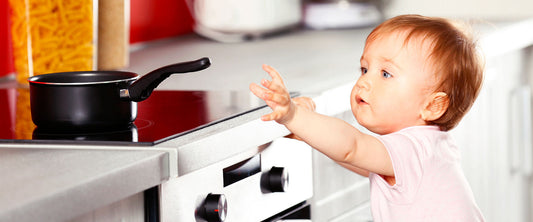 Bebé tratando de agarrar algo caliente de la cocina.