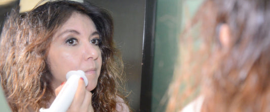 Mujer usando su DermaWand frente al espejo.