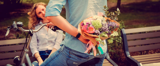 Hombre sorprendiendo a una mujer con un ramo de flores.