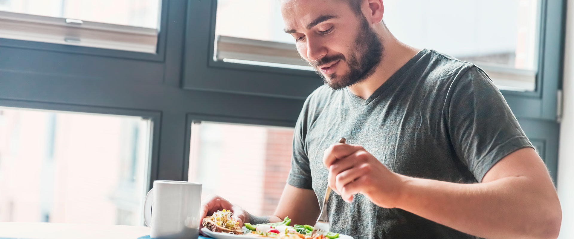 Hombre feliz comiendo ensalada.