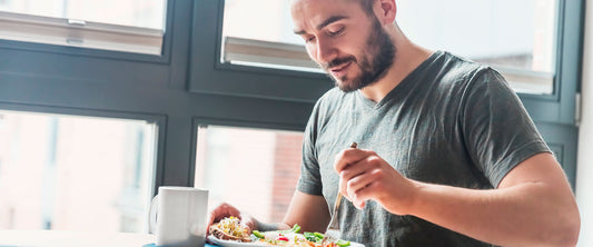 Hombre feliz comiendo ensalada.