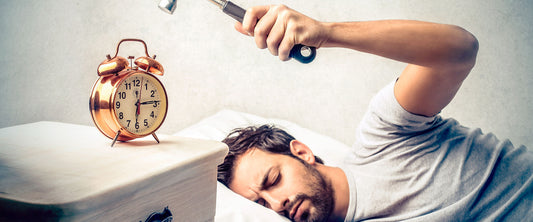 Hombre tratando de destruir su despertador.