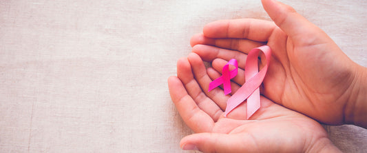 Manos de mujer con dos listones rosas, conmemorando el día de la lucha contra el cáncer de mama.