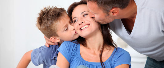 Esposo e hijo dándole un beso a la mamá por ser Día de las Madres.