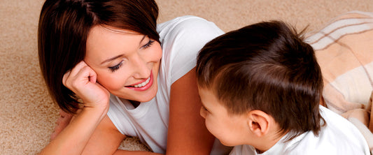 Mamá e hijo platicando alegremente sobre la alfombra.