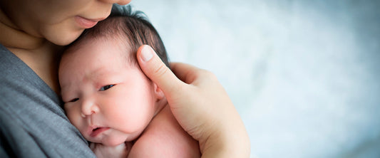 Mamá primeriza cargando a su bebé recién nacido.