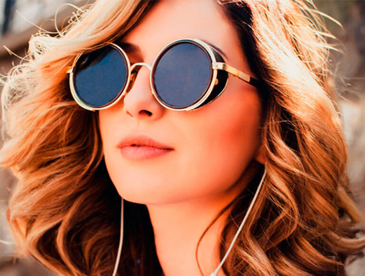 Mujer de cabello rizado, usando lentes circulares para el sol.