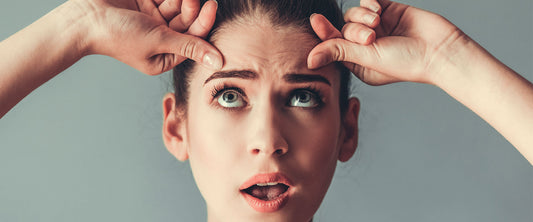 Mujer en sus treintas, estirando la piel de su rostro para evitar las arrugas.