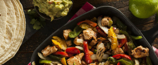 Fajitas de pollo en un sarten con guacamole y tortillas