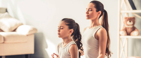 Madre e hija practicando yoga.