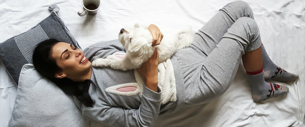 Mujer acostada con su mascota tomando café