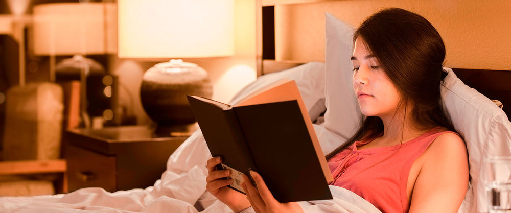 Mujer leyendo un libro para poder conciliar el sueño luego del estrés postraumático.