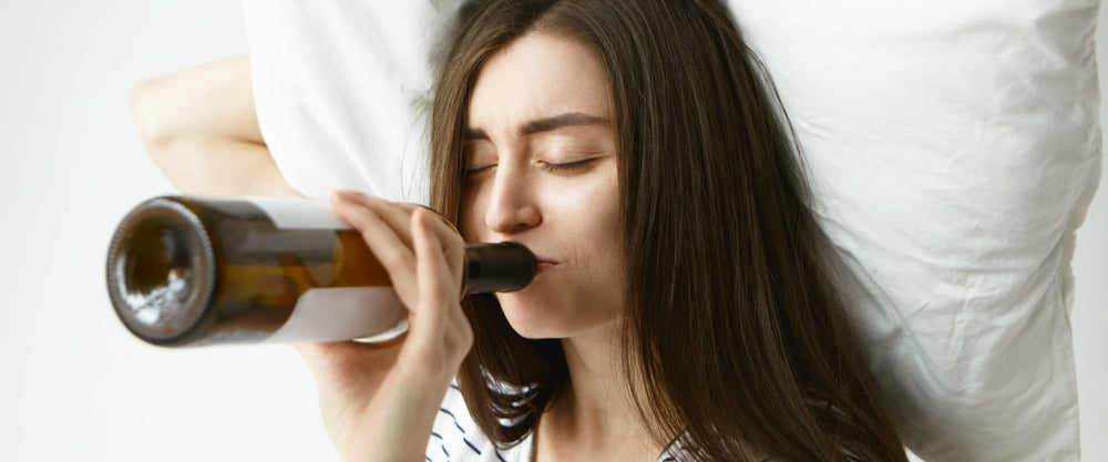 Mujer soteniendo una almohada tomando una botella de vino