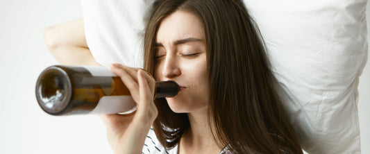 Mujer soteniendo una almohada tomando una botella de vino