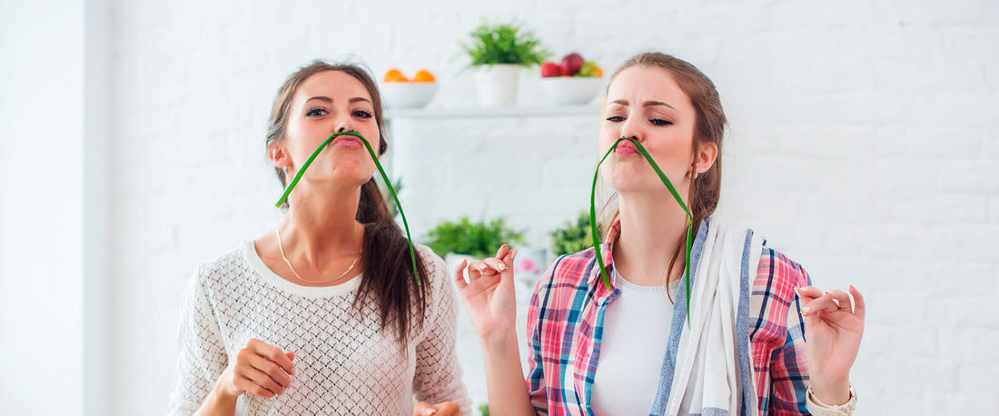 Un par de mujeres jóvenes, cocinando y divirtiéndose en la cocina.
