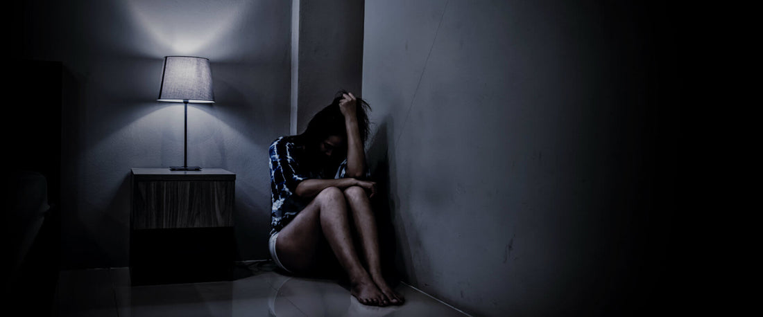 Mujer sentada en una esquina con miedo