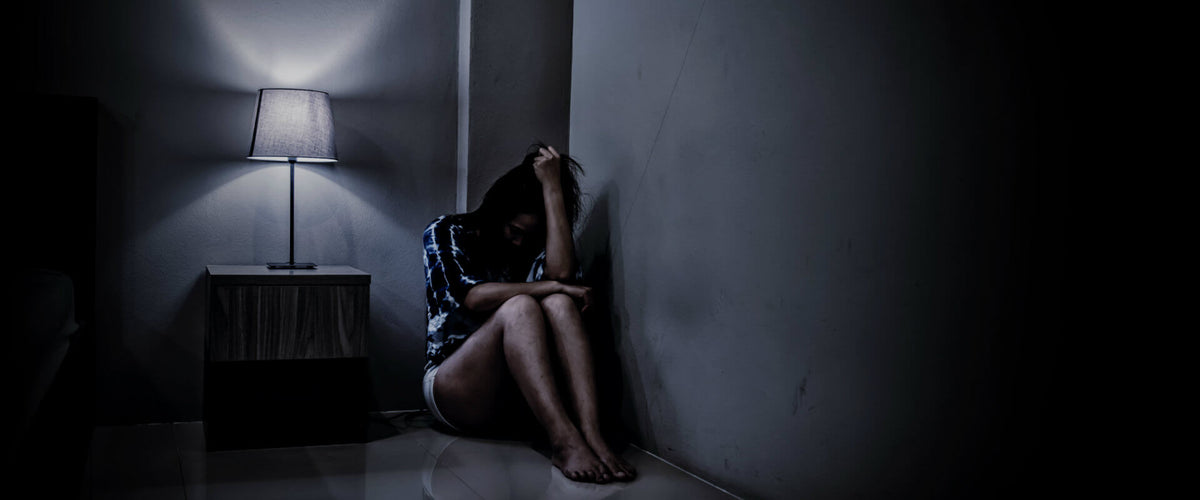 Mujer sentada en una esquina con miedo