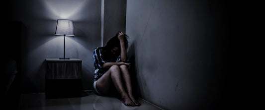 Mujer sentada en una esquina con miedo