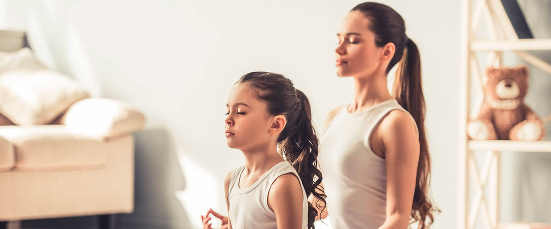 Madre e hija practicando yoga.